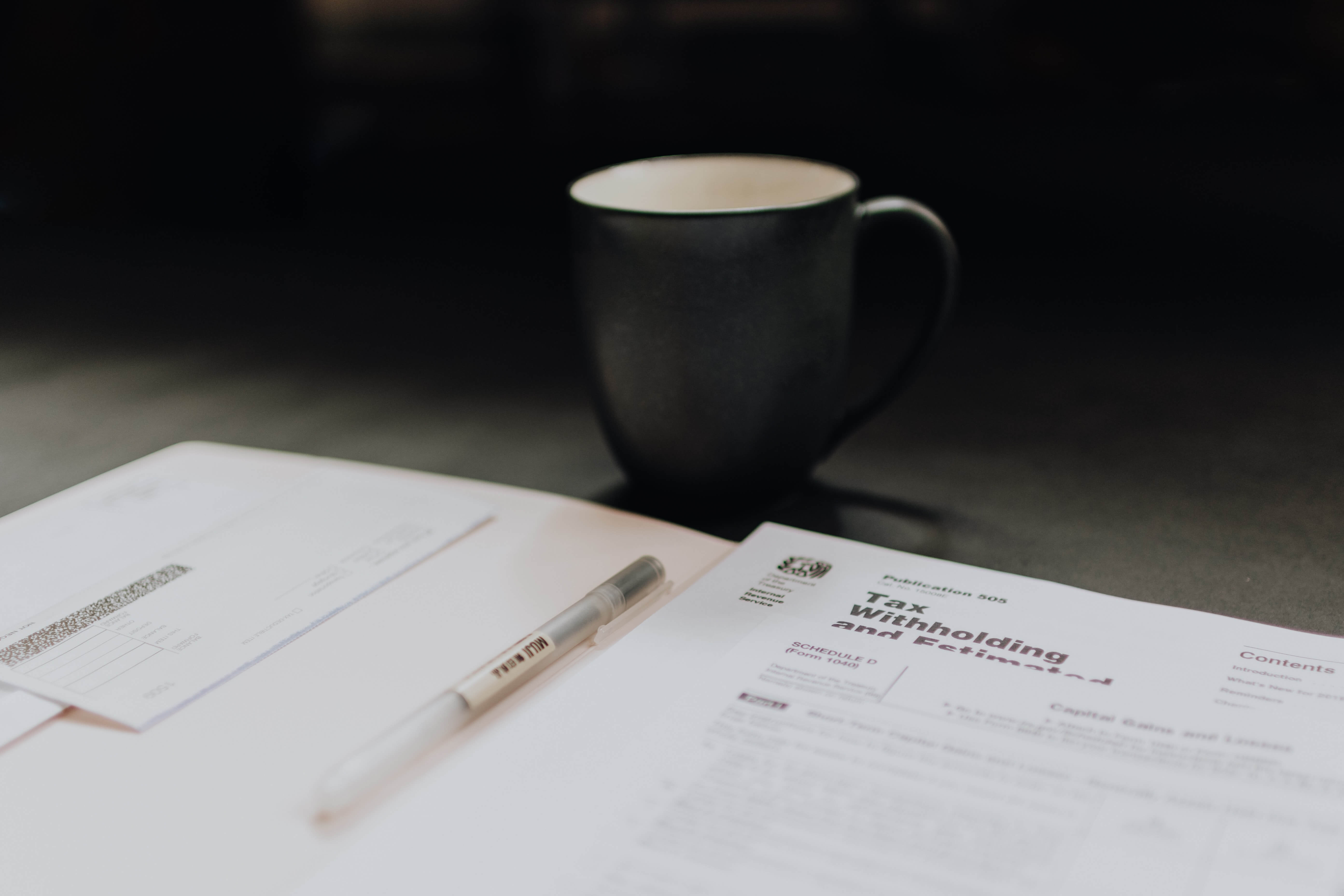 An open notebook with a coffee cup on a desk.